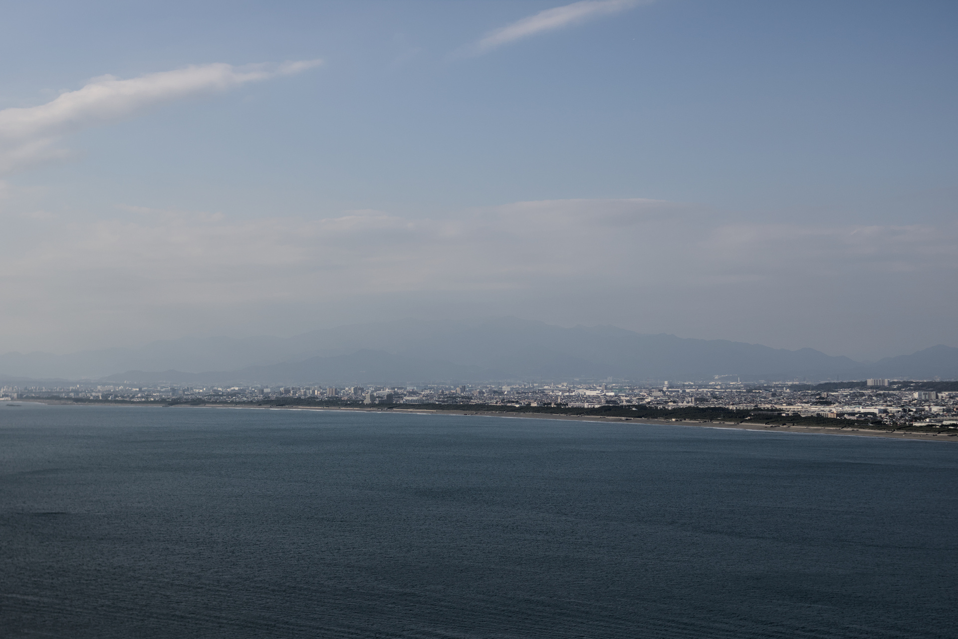 Long urban shoreline fading into the foggy distance with mountains barely visible in the background.